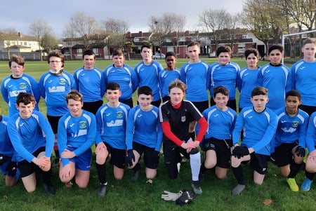 Eine Gruppe junger Fußballspielerinnen und Fußballspieler der Donahies Community School posiert auf dem Spielfeld für ein Mannschaftsfoto.