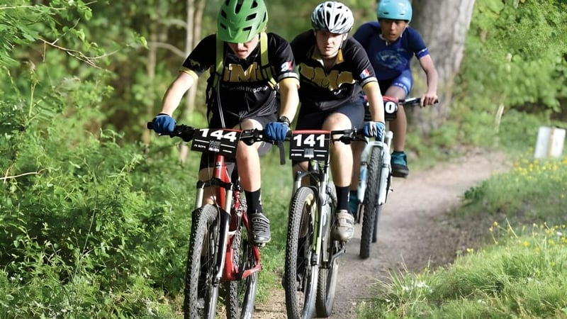Drei Radfahrer fahren auf einem Waldweg auf dem Gelände der Donahies Community School.