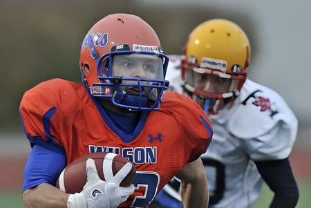 Ein Fußballspieler in orange Trikot mit dem Schriftzug Wilson steht auf dem Spielfeld der Donald A. Wilson School.