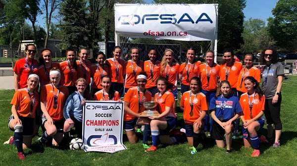 Eine Gruppe von Schülerinnen und Schülern der Donald A. Wilson School posiert vor einem FSSAA-Banner auf dem Fußballfeld.