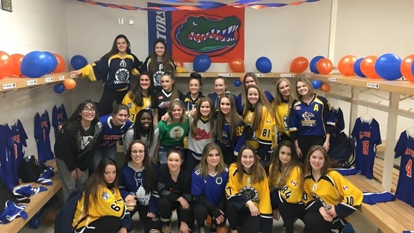 Eine Gruppe Schülerinnen der Donald A. Wilson School posiert in Sportuniformen vor dem Gator-Logo in einem dekorierten Raum.