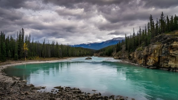 Eine ruhige Flusslandschaft mit türkisfarbenem Wasser und Bergen im Hintergrund auf dem Gelände der Dorset Collegiate.