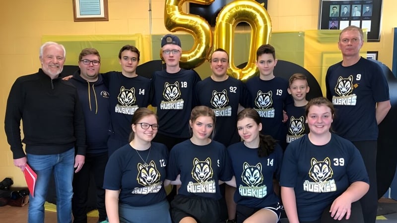 Schüler und Lehrer von Dorset Collegiate versammeln sich vor einer großen goldenen 50 als Jubiläumsfeier.