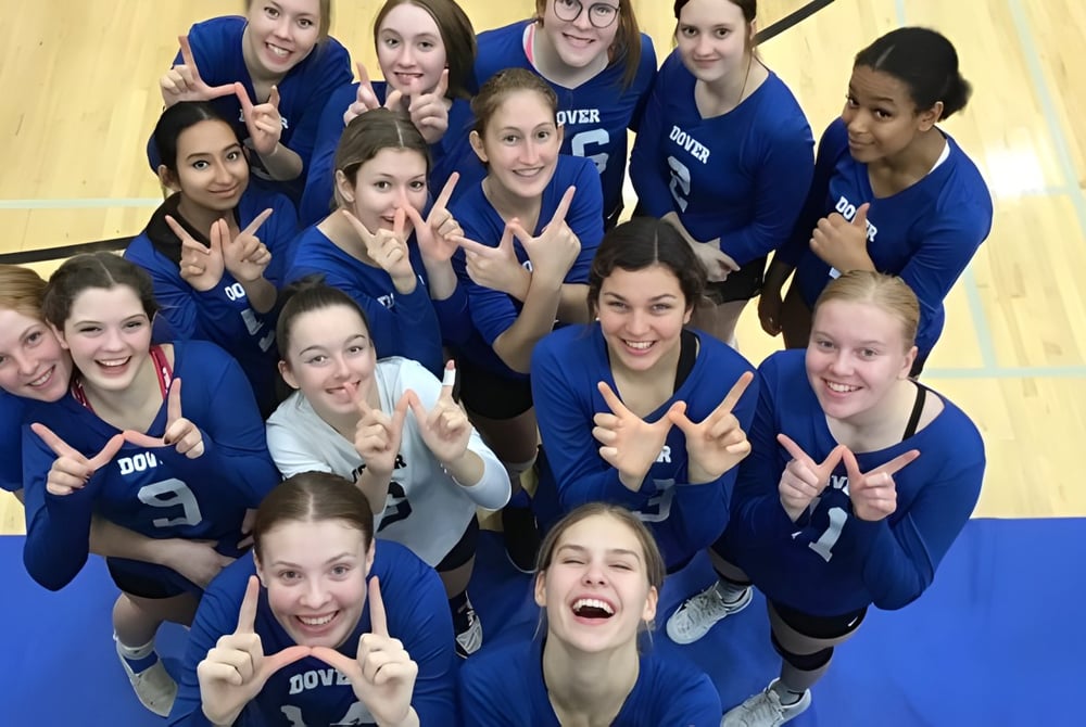 Eine Gruppe Schülerinnen der Dover Bay Secondary School zeigt im Sporthalle Peace-Zeichen und lacht gemeinsam.