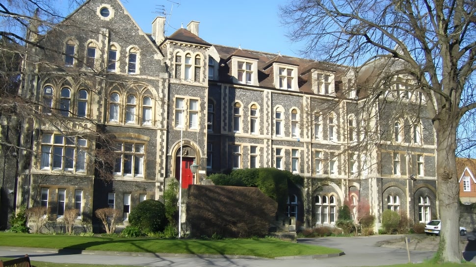 Das gotische Gebäude des Dover College steht umgeben von Bäumen und Grünflächen.