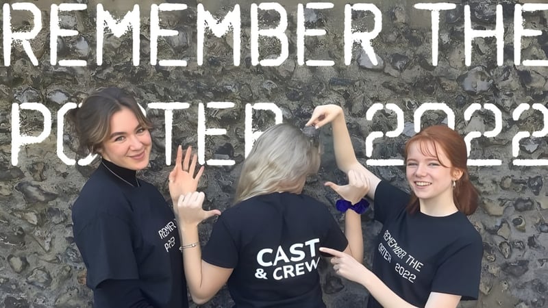 Drei Schülerinnen des Dover College posieren vor einer Wand mit Graffiti und dem Schriftzug ‚Remember the Poster 2022‘.