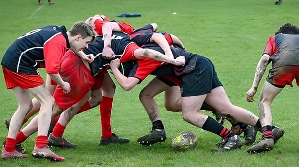 Eine Gruppe von Rugbyspielern in roten und schwarzen Trikots beim Gedränge auf dem Feld des Dover College.