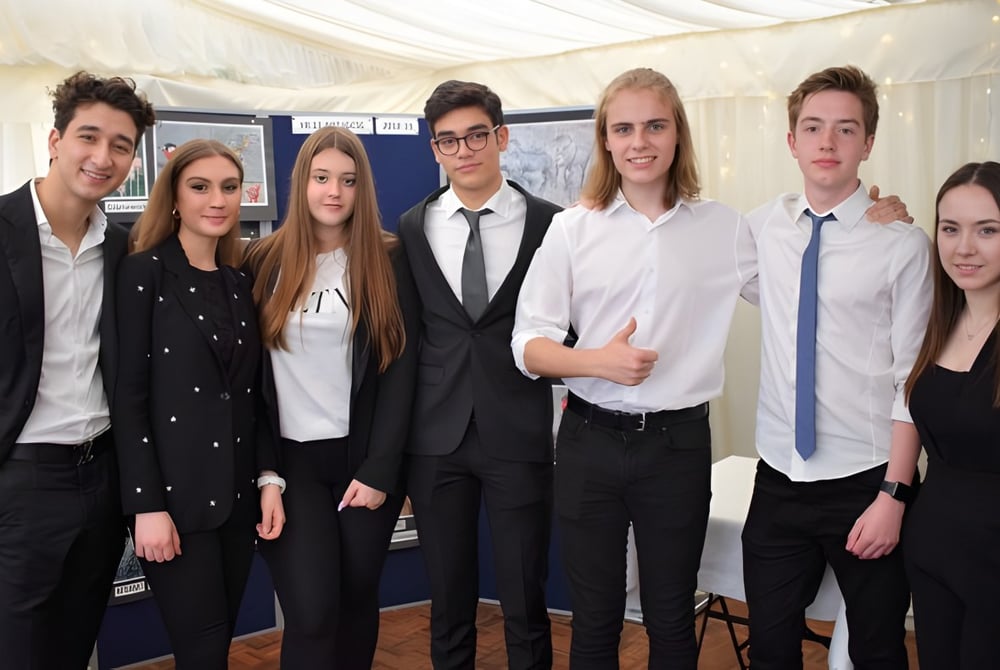 Eine Gruppe von Schülerinnen und Schülern des D'Overbroeck's College posiert in formeller Kleidung vor einem weißen Zelt.