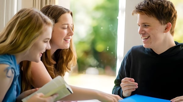 Drei Schülerinnen und Schüler von D'Overbroeck's College unterhalten sich lebhaft im Außenbereich der Schule.