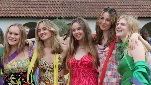 Eine Gruppe Schülerinnen posiert lachend vor einem Gebäude mit Ziegeldach auf dem Campus der Downe House School.