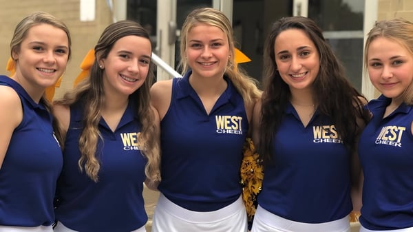 Fünf Schülerinnen des Downingtown Area School District posieren gemeinsam in ihren einheitlichen Cheerleading-Kleidern in einer Sportanlage.