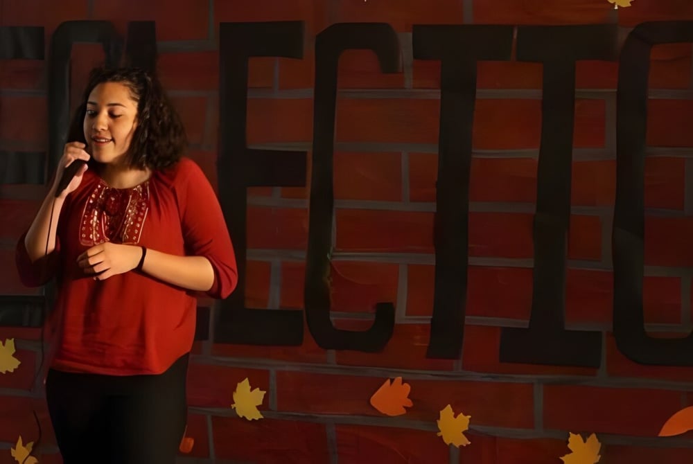 Eine Schülerin der Downtown Magnet High School steht vor einer Backsteinwand mit herbstlichen Blättern.