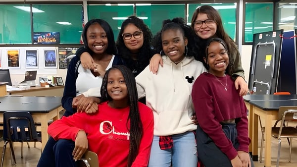 Eine Gruppe junger Schülerinnen steht gemeinsam in einem Klassenraum der Downtown Magnet High School.