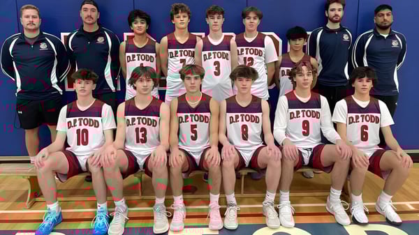 Eine Gruppe von jungen Basketballspielern posiert zusammen in der Turnhalle der D.P. Todd Secondary School.