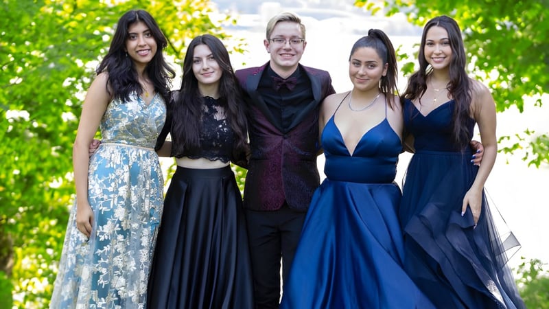 Eine Gruppe von fünf Personen zeigt sich in formeller Kleidung im grünen Außenbereich der Dr. Charles Best Secondary School.