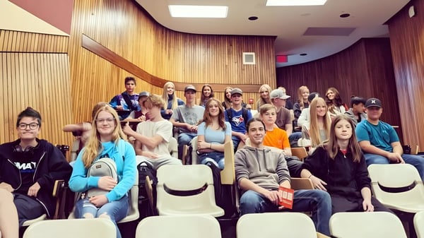 Eine Gruppe Schüler sitzt im Holzvertäfelten Raum auf dem Campus der Dr. Elliott School.