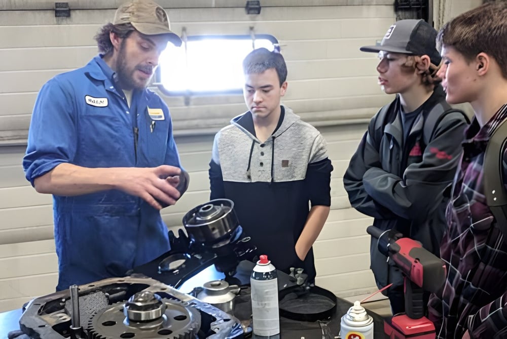 Schüler der Dr. Elliott School arbeiten gemeinsam an einem mechanischen Objekt in der Werkstatt.