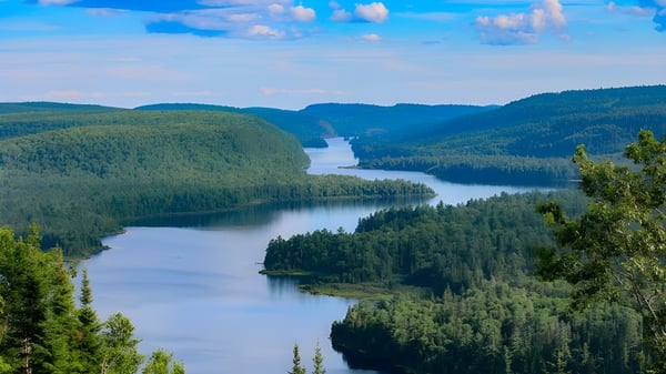 Landschaft mit Fluss und bewaldeten Bergen unter blauem Himmel auf dem Gelände der Dr. G.W. Williams Secondary School.