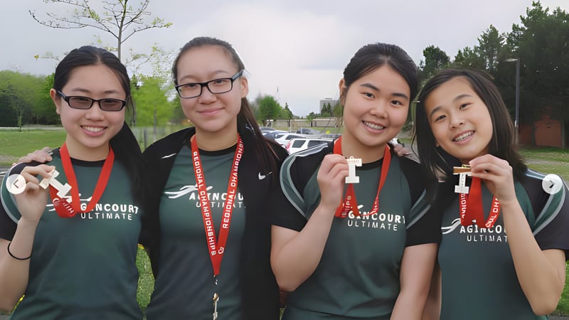 Vier Schülerinnen des Dr. Norman Bethune Collegiate Institute tragen grüne Trikots und stehen gemeinsam auf einem Spielfeld.