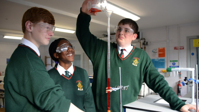 Drei Schüler der Drogheda Grammar School stehen im Klassenzimmer, wobei ein Schüler einen Glasbehälter hochhält.
