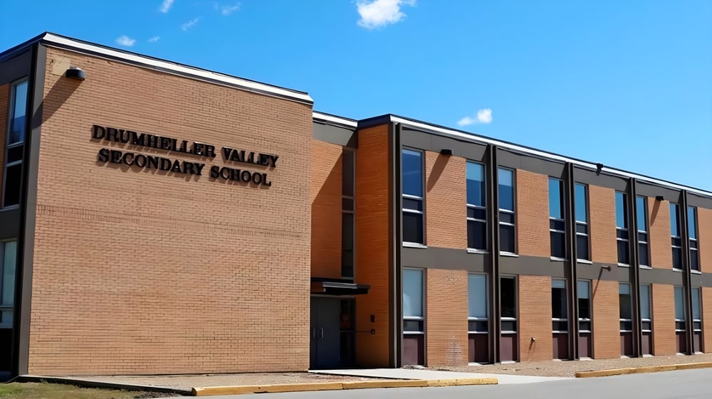 Das große Backsteingebäude der Drumheller Valley Secondary School steht unter einem bewölkten blauen Himmel.