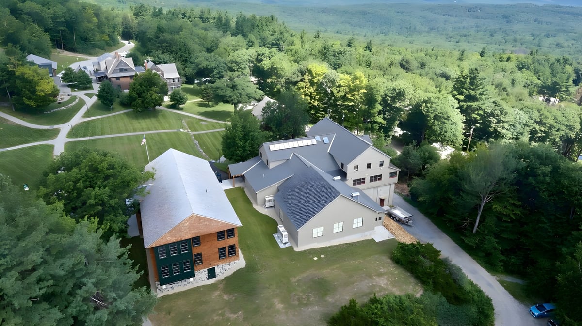 Luftaufnahme des großen mehrstöckigen Gebäudes der Dublin School umgeben von grünen Wäldern und verschlungenen Wegen.