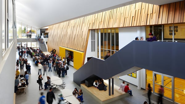 Eine belebte Innenraumaufnahme auf dem Campus der Duchess Park Secondary School mit moderner Holzverkleidung und farbigen Elementen.