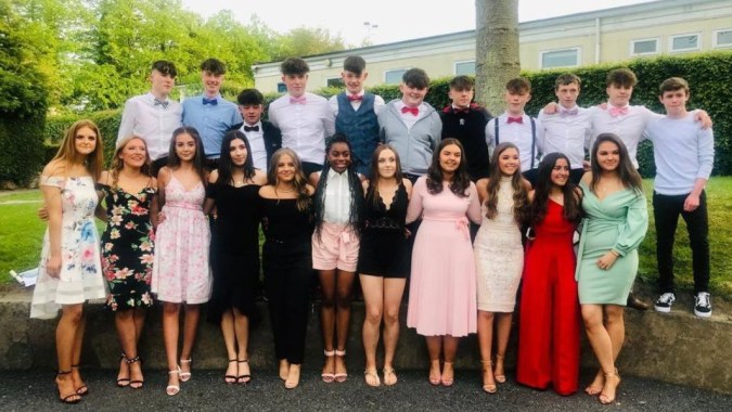 Eine Gruppe Schülerinnen und Schüler des Duiske College steht in formeller Kleidung vor einem Gebäude im Außenbereich.