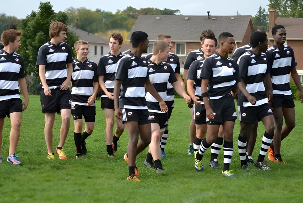 Eine Gruppe von Schülerinnen und Schülern der Dunbarton High School steht auf einem Feld mit Gebäuden und Bäumen im Hintergrund.