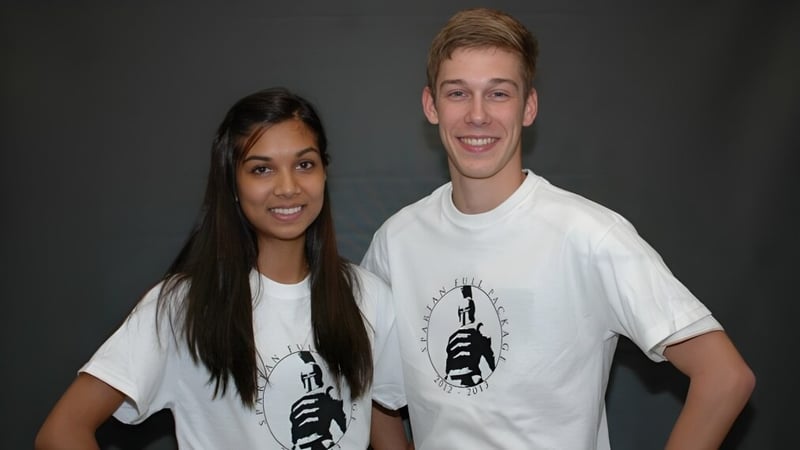 Zwei Schülerinnen und Schüler der Dunbarton High School stehen vor dunklem Hintergrund und lächeln in die Kamera.