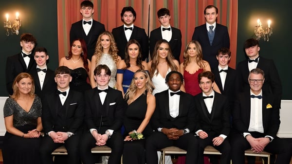 Eine Gruppe formal gekleideter Personen posiert in einem festlichen Raum auf dem Campus der Dundalk Grammar School.
