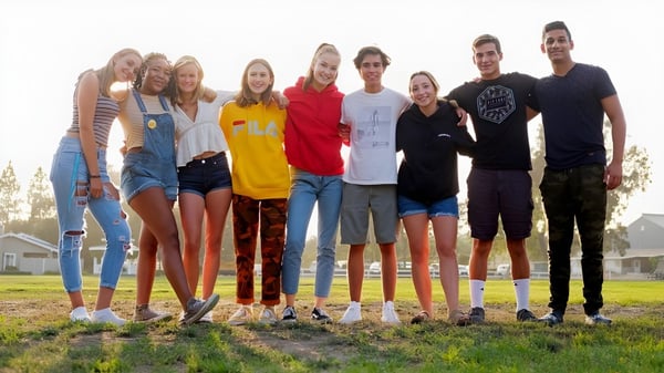 Eine Gruppe Schülerinnen und Schüler der Dunn School steht zusammen auf einer Wiese mit Häusern im Hintergrund.