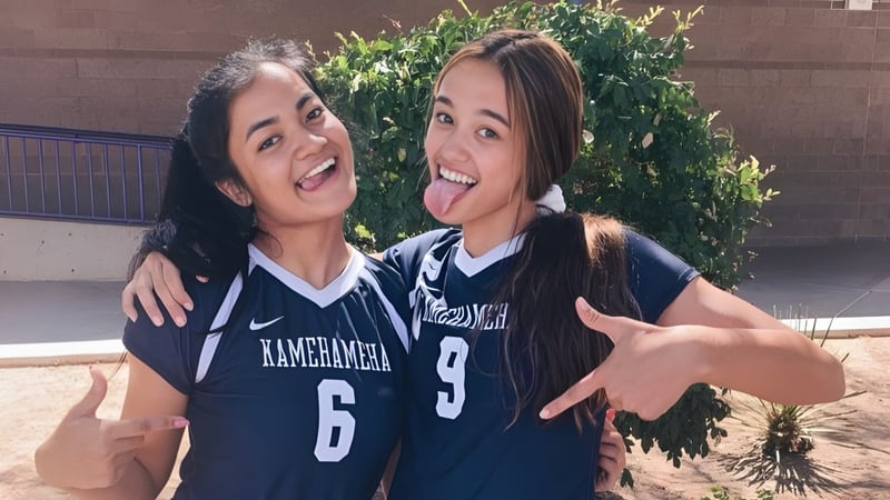 Zwei Schülerinnen der Durango High School umarmen sich draußen vor grünem Hintergrund.