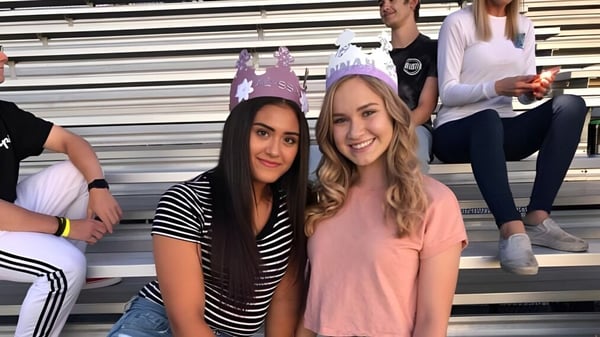 Zwei Schülerinnen posieren gemeinsam vor einer Tribüne auf dem Gelände der Durango High School.