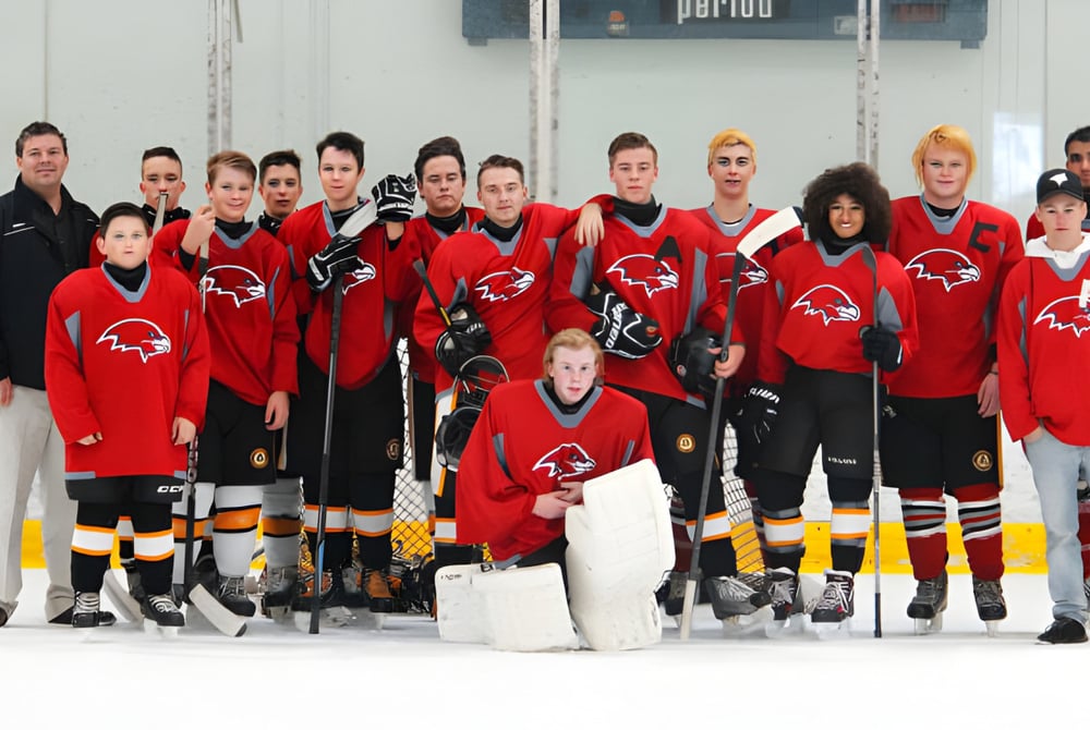 Schüler der D.W. Poppy Secondary School stehen in roten und schwarzen Trikots auf einer Eisfläche während eines Hockeyspiels.