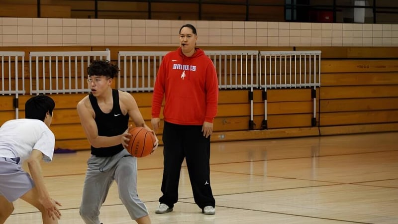 Zwei Schülerinnen der Eagle Butte High School spielen Basketball in einer Sporthalle mit Holzboden.
