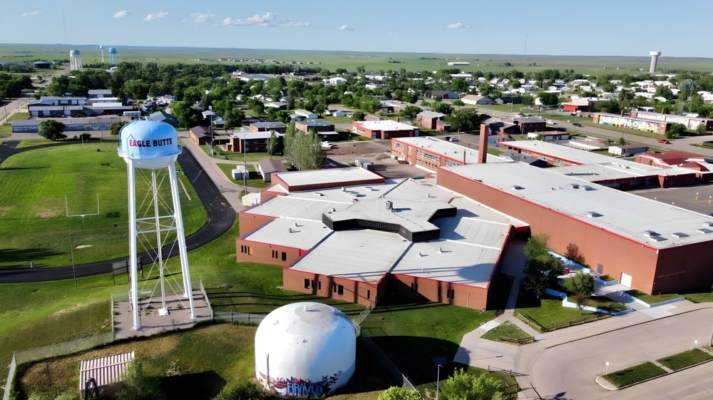Luftaufnahme einer kleinen Stadt mit Landschaft und Wasserturm in der Nähe von Eagle Butte High School.