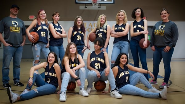 Eine Gruppe von Schülerinnen und Schülern der Eagle School posiert zusammen auf dem Basketballplatz in passenden Trikots.