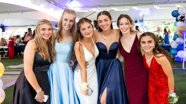 Eine Gruppe junger Frauen in festlicher Kleidung posiert draußen auf dem Campus der Earlscliffe School mit Luftballons im Hintergrund.