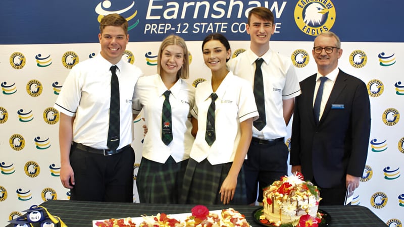 Eine Gruppe von Schülern posiert vor einem Hintergrund mit dem Logo des Earnshaw State College.