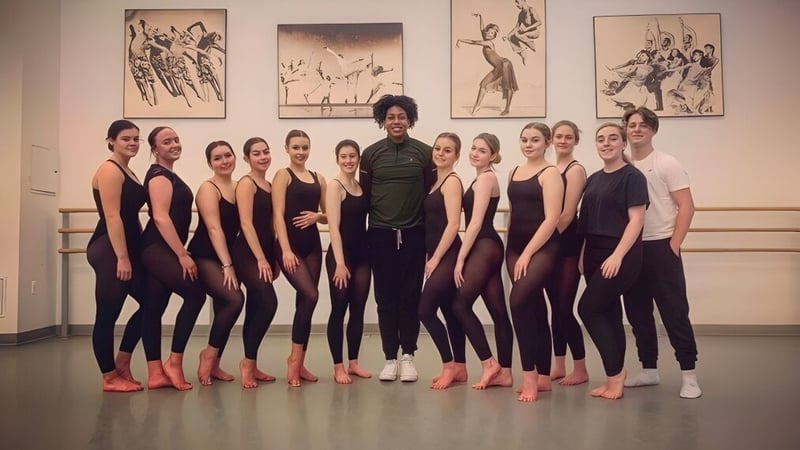 Eine Tanzgruppe von Schülern im Studio des East Sussex College Eastbourne steht zusammen vor tanzbezogener Wanddekoration.