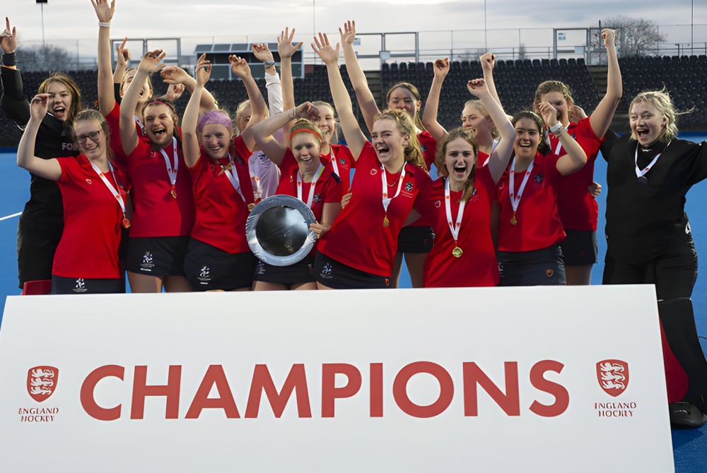 Schüler der Eastbourne Academy feiern auf dem Sportplatz und halten ein Champions-Schild hoch.