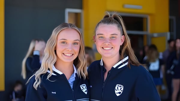 Zwei Schülerinnen in Schuluniform posieren vor einer gelben Wand auf dem Campus der Eastern Fleurieu R-12.