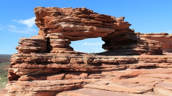 Eine natürliche Felsenbogenformation aus rötlich-braunem Sandstein ist vor klarem Himmel in der Nähe der Eastern Hills Senior High School zu sehen.