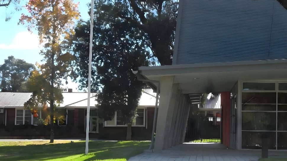 Das Wohngebäude mit überdachtem Eingang steht auf dem Gelände der Eastern Hills Senior High School und ist von Bäumen umgeben.
