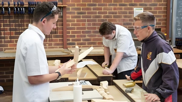 Schüler der Eastern Hills Senior High School arbeiten gemeinsam an einem Holzprojekt in der Werkstatt.