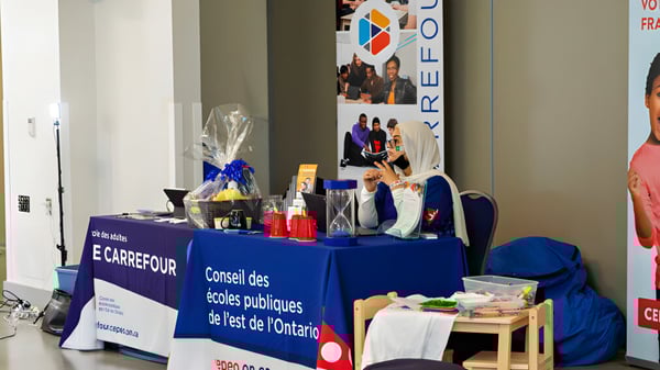 Ein Informationsstand des Eastern Ontario Public Schools mit einem Schild in einem Flur mit Postern an den Wänden.