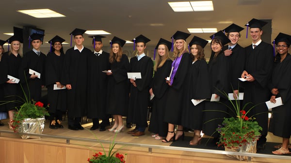 Eine Gruppe von Absolventinnen und Absolventen der Eastside Secondary School steht in einem Raum mit Pflanzen und Beleuchtung.