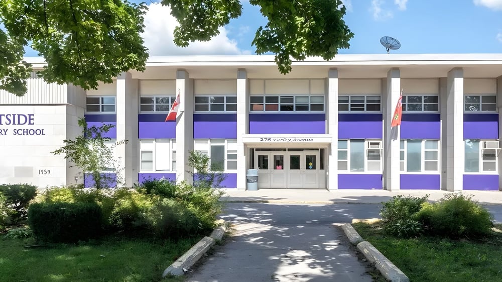 Das moderne zweistöckige Schulgebäude der Eastside Secondary School ist von Grünanlagen und einem gepflasterten Weg umgeben.
