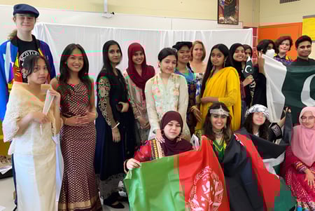 Eine Gruppe Schülerinnen in traditioneller und moderner Kleidung im farbenfrohen Klassenzimmer der Eastside Secondary School.